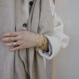 Wrist with five gold bracelets by Melanie Pigeaud, including the drawn chain bracelet in 14K gold.