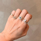 Hand wearing multiple rings with a neutral background