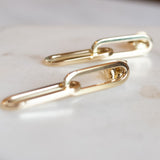 Close up Melanie Pigeaud drawn earrings in 14k gold presented on marble
