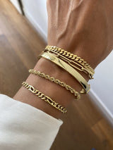 Wrist with five gold bracelets by Melanie Pigeaud, including the Squared slave bracelet 14k gold 6mm