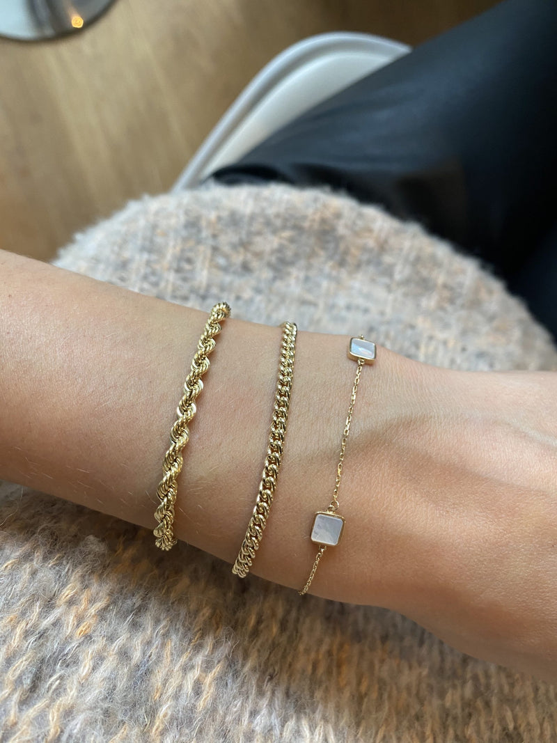 Wrist with three gold bracelets by Melanie Pigeaud, including the gourmet round chain