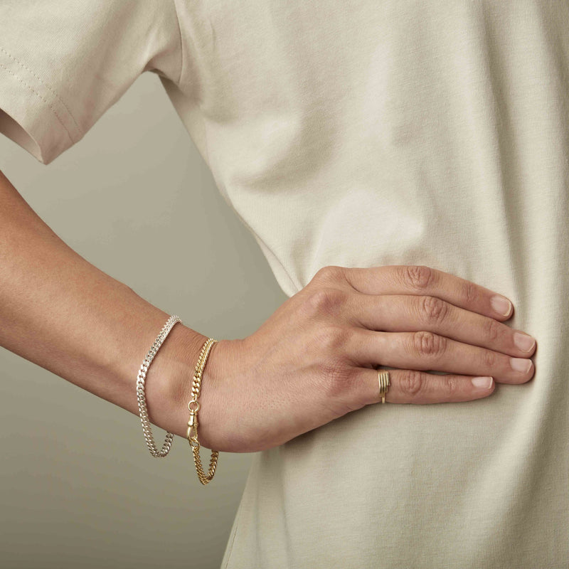 Wrist with two gold bracelets by Melanie Pigeaud, including the No.5 connector sterling silver.