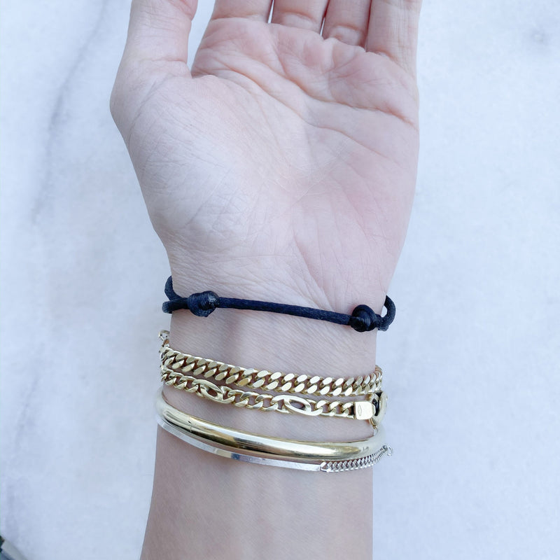 Wrist with MP together bracelet black 14k gold by Melanie Pigeaud and 3 other bracelets. from a under view
