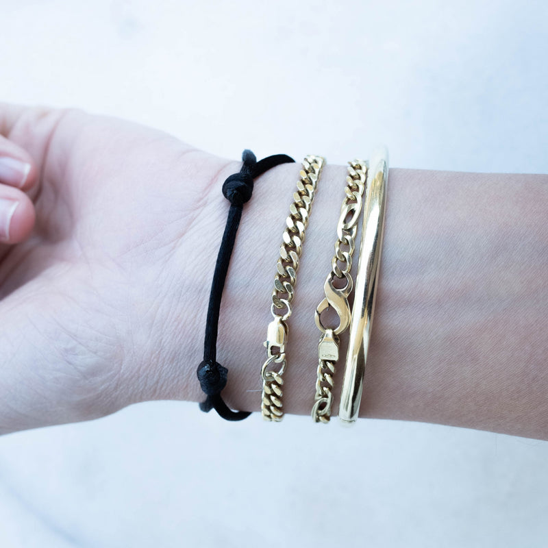 Wrist with MP together bracelet black 14k gold by Melanie Pigeaud and 3 other bracelets. from a under view