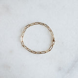 Drawn chain bracelet in 14k gold by Melanie Pigeaud presented on marble stone. 