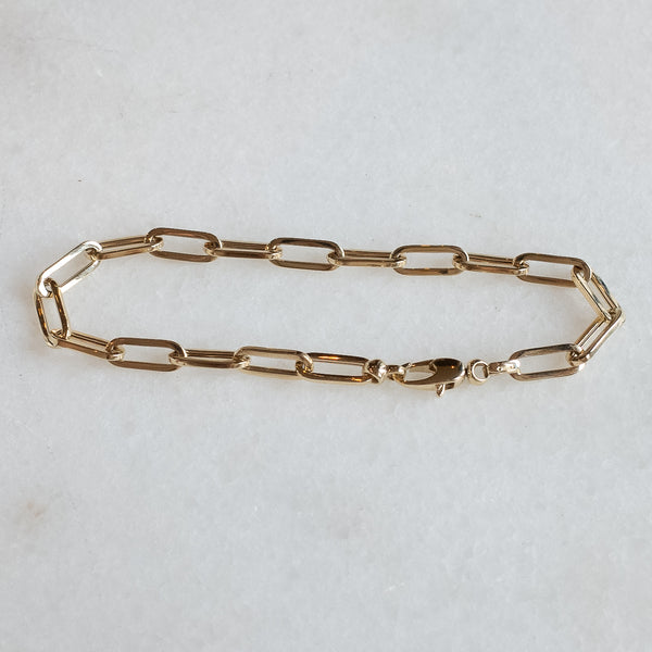 Drawn chain bracelet in 14k gold by Melanie Pigeaud presented on marble stone.