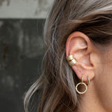 Ear with Melanie Pigeaud circle of empower earring in 14k gold and two Melanie Pigeaud earcuffs in 14k gold