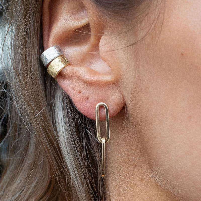 Ear with Melanie Pigeaud drawn earring in 14k gold and two Melanie Pigeaud ear cuffs in sterling silver and 14k gold