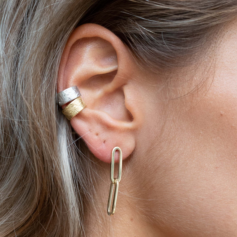 Ear with Melanie Pigeaud drawn earring in 14k gold and two Melanie Pigeaud earcuffs in sterling silver and 14k gold