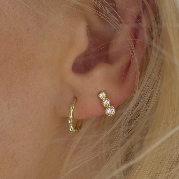 Ear with Melanie Pigeaud bamboo hoops earrings in 9k gold and Melanie Pigeaud zirconia dots earring in 9k gold