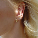 Ear with Melanie Pigeaud zirconia studs leaf 9k gold earring in 9k gold and Melanie Pigeaud bamboo hoops earring in 9k gold