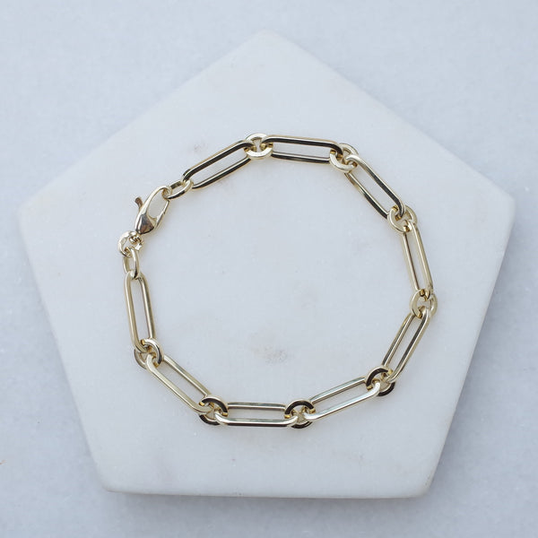 Inter drawn chain bracelet 14k gold by Melanie Pigeaud presented on marble stone