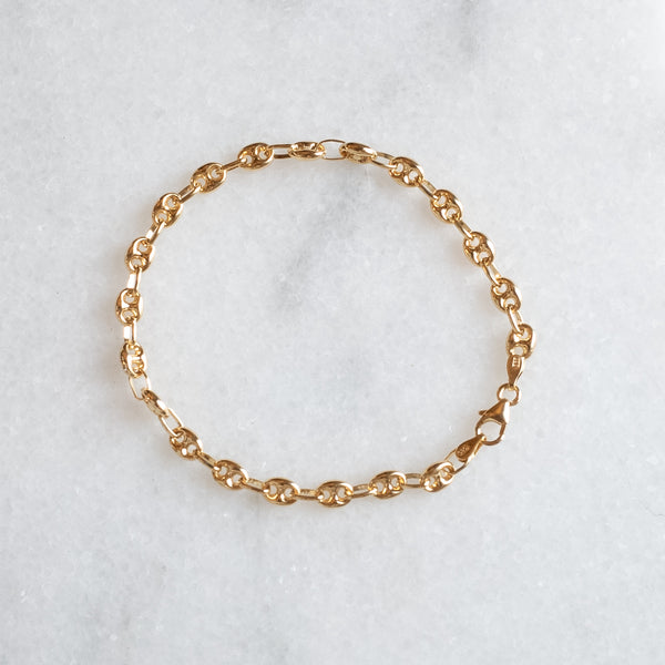 coffee bean chain bracelet of 14k by Melanie Pigeuad presented on a marble stone.
