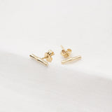 Melanie Pigeaud bamboo studs earrings in 9k gold lying down on fabric