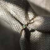 Melanie Pigeaud ring with peridot stone in 9k gold presented around fabric