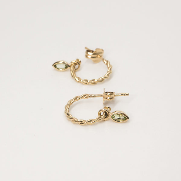 Melanie Pigeaud rope earrings with a peridot stone in 9k gold lying down