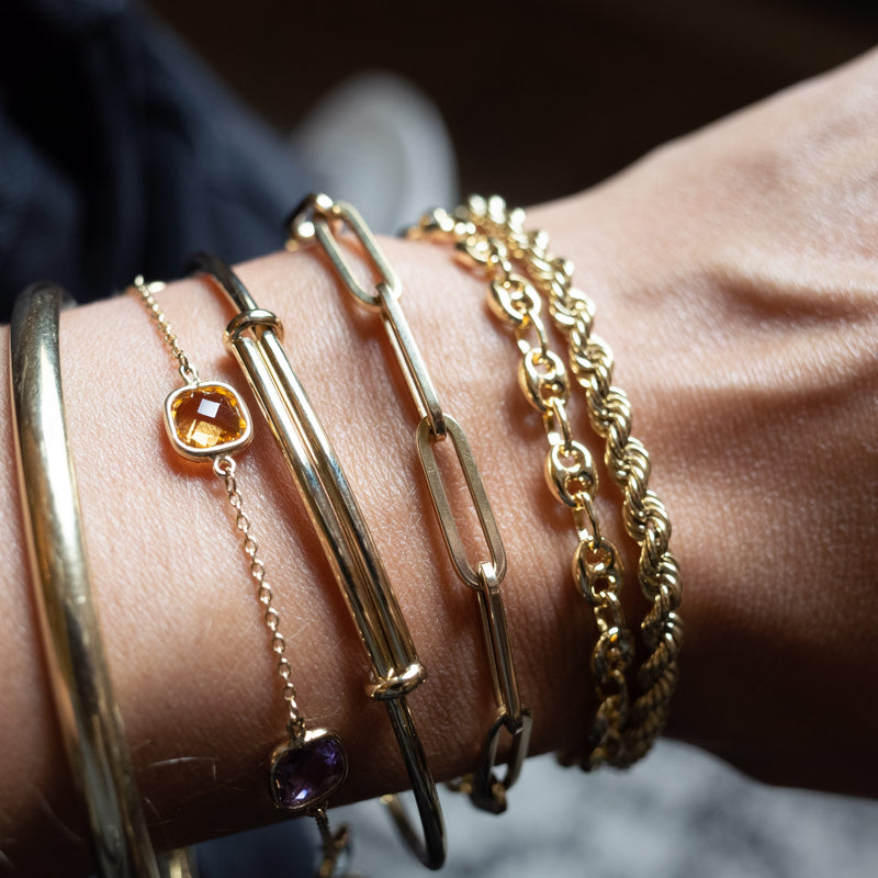 Wrist with five gold bracelets by Melanie Pigeaud, including the drawn chain bracelet in 14K gold.  