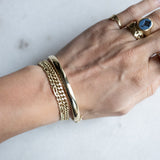 Wrist with three gold bracelets by Melanie Pigeaud, including the Slave bracelet 14k gold
