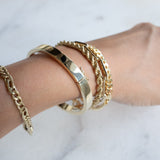 Wrist with five gold bracelets by Melanie Pigeaud, including the Squared slave bracelet 14k gold 6mm.