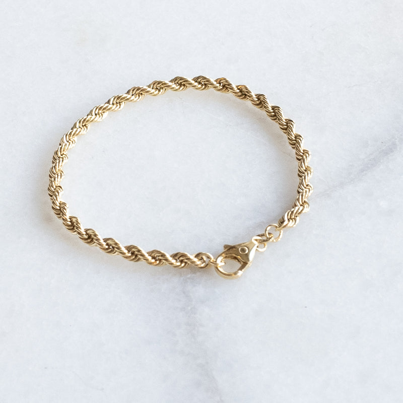 Wired bracelet 14k gold by Melanie Pigeuad presented on a marble stone