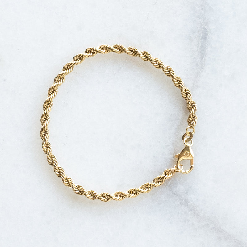 Wired bracelet 14k gold by Melanie Pigeuad presented on a marble stone.