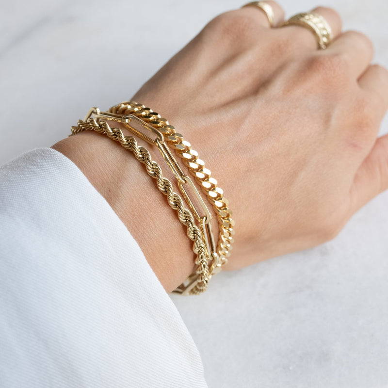 Wrist with three gold bracelets by Melanie Pigeaud, including the Wired bracelet 14k gold.